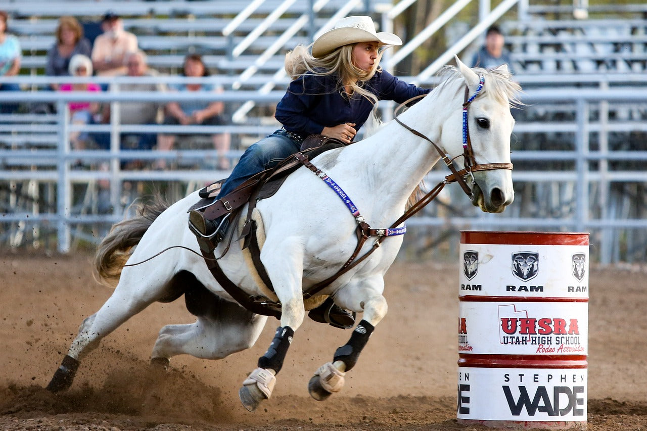 A rider racing a horse around a barrel at a rodeo